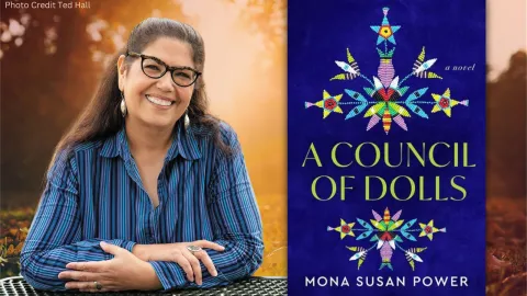 Photo of Mona Susan Power outside on a park table during the fall season. An image of her book, A Council of Dolls's cover art is placed next to her image.